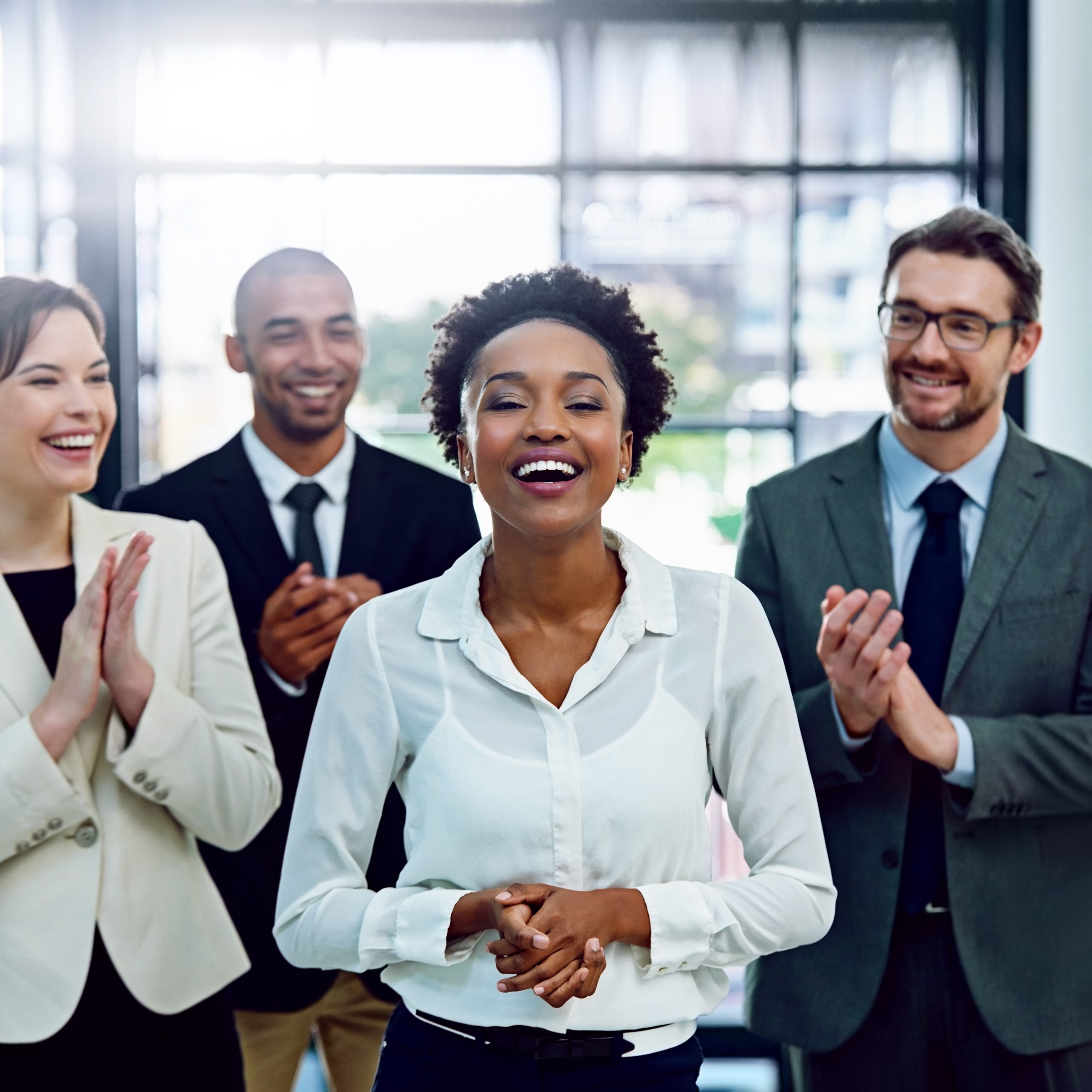 Portrait of a succesful businesswoman being applauded by her colleagues in the office.